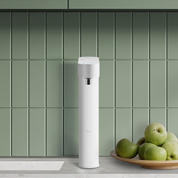 싱크대 옆쪽에 빌트인된 LG 퓨리케어 정수기. 세련된 화이트 컬러의 슬림한 디자인이 깔끔한 주방 공간과 조화를 이루며, 옆에는 신선한 녹색 사과가 담긴 접시가 놓여 있어 자연스러운 분위기를 연출함.