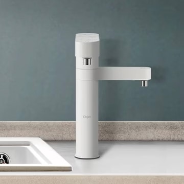 LG 퓨리케어 정수기 주방 싱크대 옆에 설치된 모습. 모던한 화이트 색상의 본체와 깔끔한 디자인이 돋보인다.