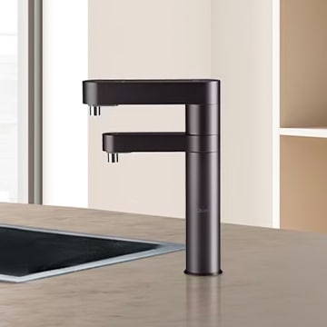 블랙 색상의 LG 퓨리케어 정수기 듀얼 정수가 넓은 조리 공간 위에 설치된 모습. 모던하고 고급스러운 분위기가 돋보이며, 듀얼 출수 기능으로 편리한 사용이 가능함을 보여준다.