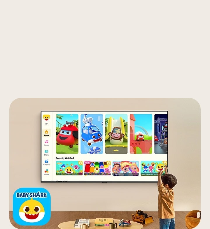 장난감이 있는 거실에서 벽에 걸린 LG TV를 통해 핑크롱을 보는 어린 아이.
