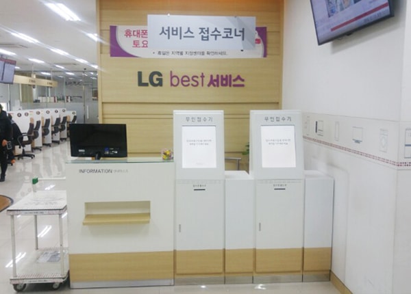 사하서비스센터의 안내데스크 오른쪽에 셀프 접수기가 있습니다. 앞쪽 천장에 '서비스 접수코너'라는 팻말이 달려 있으며, 뒤쪽 벽면에는 'LG best 서비스'라고 적혀 있습니다.