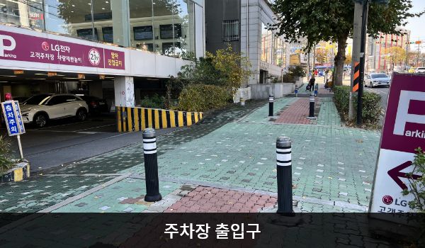 남인천서비스센터의 P'라는 글자가 크게 적힌 보라색 입간판 좌측으로 주차장 출입구가 있습니다. 출입구 위쪽에는 '고객주차장 차량제한높이 2.1m', '탑차 진입금지'라고 적혀 있습니다.