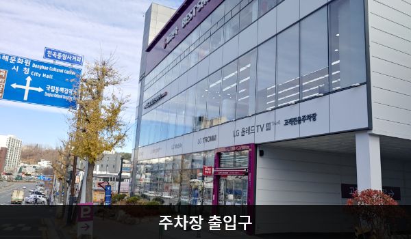 동해서비스센터의 고객전용 주차장' 간판이 있는 방향으로 들어오셨다면 건물 뒤편에 지상 주차장이 있습니다. 건물 뒤에서도 들어갈 수 있는 여닫이문 출입구가 있습니다. 문 앞에 '2F LG BEST 서비스센터'라고 적힌 안내문이 있습니다.