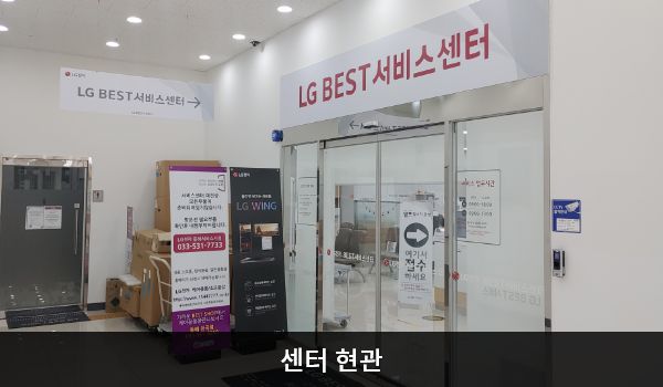동해서비스센터의 2층 현관문 위쪽에 'LG BEST 서비스센터'라는 문구가 적혀 있습니다. 현관문은 자동문이고 문 왼쪽에 열림 버튼이 있습니다. 들어오시면 앞에 접수 창구가 있습니다.