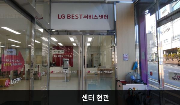거제서비스센터의 1층 출입구에 들어오자마자 오른쪽에 서비스센터 현관문이 있습니다. 문 위쪽 큰 흰색 간판에 'LG BEST 서비스센터'라고 적혀 있습니다. 현관문은 여닫이문이고, 들어오시면 앞에 셀프 접수기와 접수 창구가 있습니다.