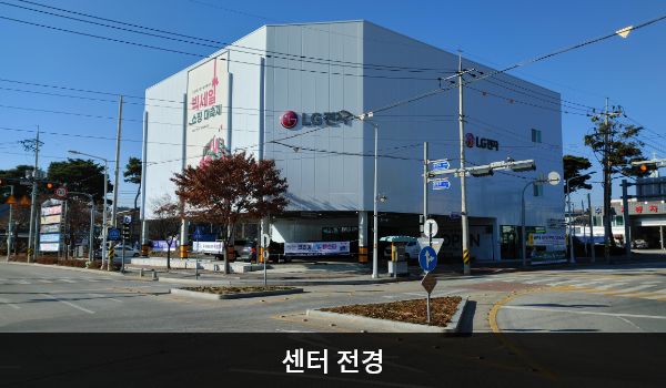 남원서비스센터의 흰색 다각형 모양의 건물에 창문이 거의 없습니다. 1층에 매장과 주차장이 함께 있고, 건물에 'LG전자'라고 쓰여 있습니다.
