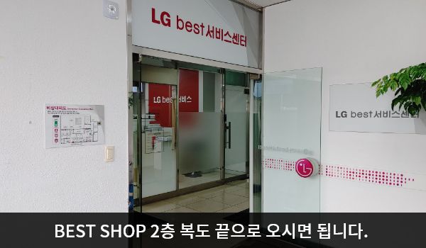 밀양서비스센터의 2층 현관문 위쪽 큰 흰색 간판에 'LG BEST 서비스센터'라고 적혀 있습니다. 현관문은 여닫이문입니다. 여닫이문을 열고 들어간 후에 여닫이문이 한 번 더 있습니다.