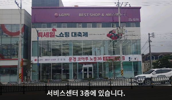 문경서비스센터의 정육면체에 가까운 건물 3층 붉은 간판에 'LG전자 BEST SHOP & 서비스센터'라고 적혀 있습니다. 건물에 유리창이 크고 많습니다.