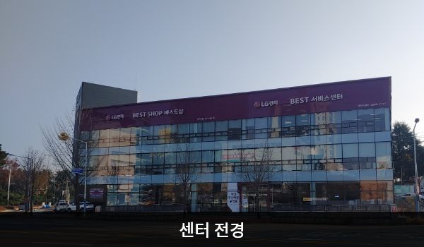 서전주서비스센터의 서비스센터 건물은 전체가 유리창으로 되어 있습니다. 건물 꼭대기 간판에 흰색 글씨, 분홍색 바탕으로 'LG전자 BEST SHOP 베스트샵'이라고 쓰여 있습니다.