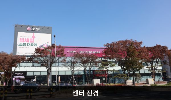 동대전서비스센터의 가로로 길고 낮은 건물 2층 붉은 간판에 'LG전자 BEST SHOP 베스트샵'이라고 적혀 있습니다. 건물 전체에 유리창이 크고 많습니다.