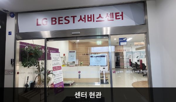 태백서비스센터의 2층 현관문 위쪽에 'LG BEST 서비스센터'라는 문구가 적혀 있습니다. 현관문은 자동문이고 오른쪽 문 중앙에 열림 버튼이 있습니다. 들어오시면 앞에 셀프 접수기와 접수 창구가 있습니다.