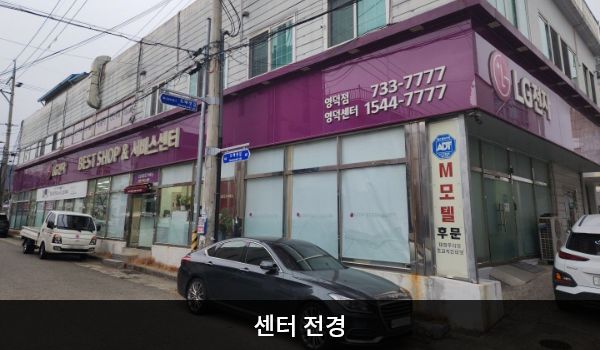 영덕서비스센터의 서비스센터 건물은 가로로 길고 베스트샵과 서비스센터가 모두 1층에 있습니다. 건물 1층 간판에 흰색 글씨, 분홍색 바탕으로 'LG전자 BEST SHOP 베스트샵', 'LG전자 BEST 서비스센터'라고 쓰여 있습니다.
