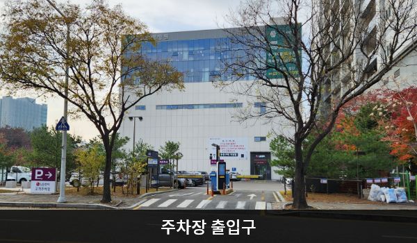 일산서비스센터의 건물 뒤쪽에 지상 주차장이 있습니다. 'P'라는 글자가 크게 적힌 회색 입간판 우측으로 주차장 출입구가 있습니다. 주차장 출입구로 들어가면 앞쪽에 건물 출입구가 보입니다.