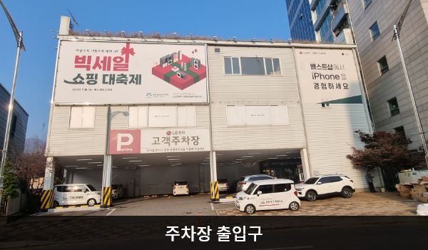 광명서비스센터의 건물 뒤편에 지상 주차장이 있습니다. 'Parking', 'LG전자 고객주차장'이라고 쓰여 있습니다. 주차장을 바라봤을 때 건물 오른쪽에 건물로 들어가는 출입구가 있습니다.