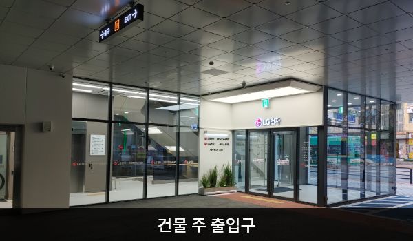 화정서비스센터의 건물 주 출입구 위에는 흰색 바탕에 'LG전자' 문구가 적혀 있습니다. 출입문 앞에 점자 블록이 있습니다.