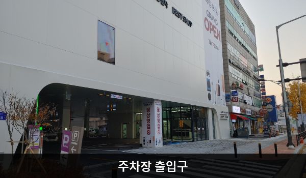 화정서비스센터의 건물 1층이 주차장입니다. 주차장 출입구는 건물 정면에 있습니다. 출입구 왼쪽에 'P', 'LG전자 고객주차장'이라고 적힌 갈색 입간판이 있습니다.