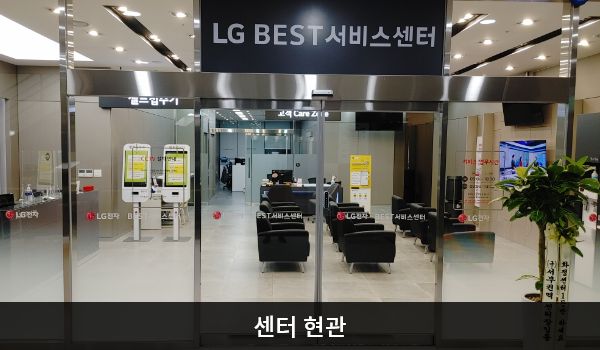 화정서비스센터의 센터 현관 위쪽에 'LG BEST 서비스센터'라는 문구가 적혀 있습니다. 자동문을 열고 들어가면 정면에 대기 의자가 있고, 정면 좌측에 셀프 접수기가 있습니다.