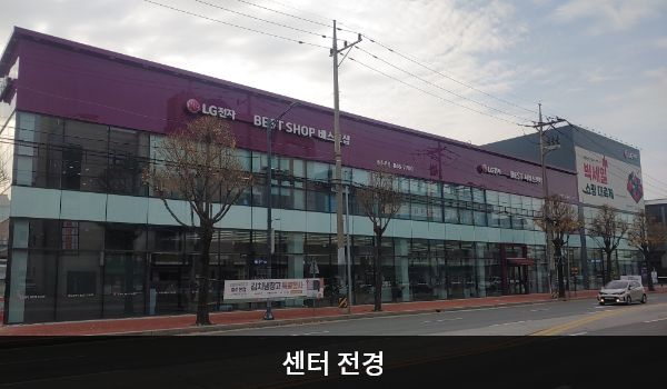 충주서비스센터의 건물 3층 붉은 바탕에 'LG전자 BEST SHOP'이라고 쓰여 있습니다. 건물 전체에 유리창이 크고 많습니다.