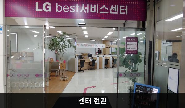 송파서비스센터의 센터 현관 위쪽에 'LG best 서비스센터'라는 문구가 적혀 있으며, 그 아래에 자동문이 있습니다. 문을 열고 들어가면 좌측에 대기 의자가 있습니다.