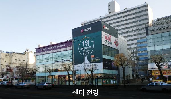 속초서비스센터의 서비스센터 건물은 유리창이 크고 많습니다. 건물 위 간판에 'LG전자 BEST SHOP'이라고 쓰여 있습니다.