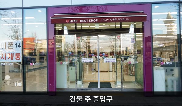 속초서비스센터의 대로 앞, 건물 중앙에 자동문 출입구가 있습니다. 문 앞에 점자블록이 있습니다. 자동문을 열고 들어간 후, 여닫이문이 한 번 더 있습니다.