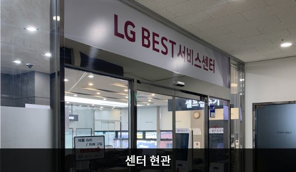 안양서비스센터의 센터 현관 위쪽에 'LG BEST 서비스센터'라는 문구가 적혀 있으며, 그 아래에 유리로 된 자동문이 있습니다. 문을 열고 들어가면 오른쪽에 셀프 접수기가 있습니다.