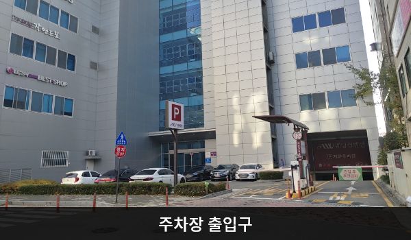 안산서비스센터의 건물 뒤쪽에 주차장 출입구가 있습니다. 차량 제한 높이는 2.2m입니다. 출입구 왼쪽에 'P'라고 적힌 입간판이 있습니다.