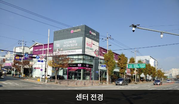 광산서비스센터의 사거리 모퉁이에 센터 건물이 있습니다. 건물 2층 붉은 간판에 'LG전자 BEST SHOP 베스트샵'이라고 적혀 있으며, 검은색 건물 외벽에는 'LG전자' 간판이 붙어 있습니다.