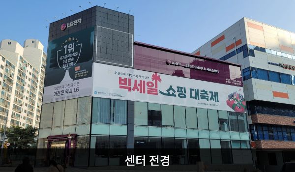 남동서비스센터의 다각형의 건물 2층 붉은 간판에 'LG전자 BEST SHOP & 서비스센터'라고 적혀 있습니다. 건물에 유리창이 크고 많습니다.
