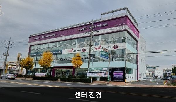 진주서비스센터의 서비스센터 건물은 가로로 길고 창문이 많습니다. 건물 꼭대기 간판에 흰색 글씨, 분홍색 바탕으로 'LG전자 BEST SHOP 베스트샵', 'LG전자 BEST 서비스센터'라고 쓰여 있습니다.