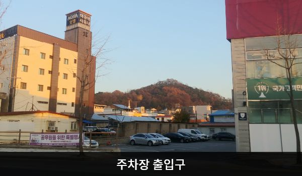 정읍서비스센터의 건물 왼쪽에 지상 주차장이 있습니다. 주차장 출입구 오른쪽에 'P'라는 글자가 적힌 갈색 입간판이 있습니다.
