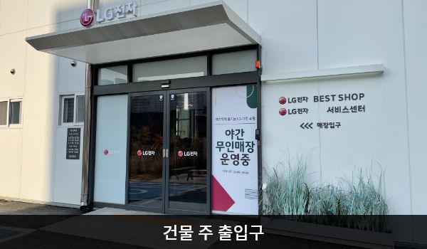 아산서비스센터의 건물 주 출입구 위에는 'LG전자' 문구가 적혀 있습니다. 자동문으로 되어 있으며, 양쪽 문 안쪽에 문 열림 버튼이 있습니다.