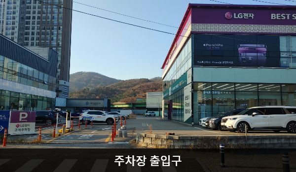 남양주서비스센터의 건물 왼쪽에 주차장 출입구가 있습니다. 출입구 왼쪽에 'P', 'LG전자 고객주차장'이라고 적힌 보라색 입간판이 있습니다.