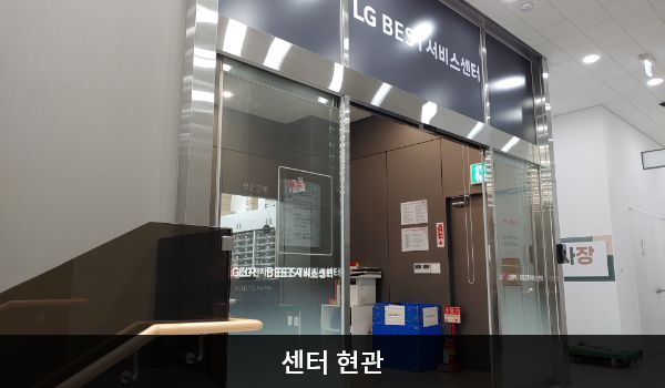 서안산서비스센터의 4층 현관문 위쪽 큰 회색 간판에 'LG BEST 서비스센터'라고 적혀 있습니다. 현관문은 자동문입니다. 들어오시면 앞에 셀프 접수기와 접수 창구가 있습니다.