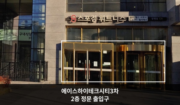 영등포서비스센터의 정문 출입구 위에는 '스포짐 휘트니스'라는 간판이 있습니다. 왼쪽에는 여닫을 수 있는 유리문이 있고, 오른쪽에는 회전문이 있습니다.