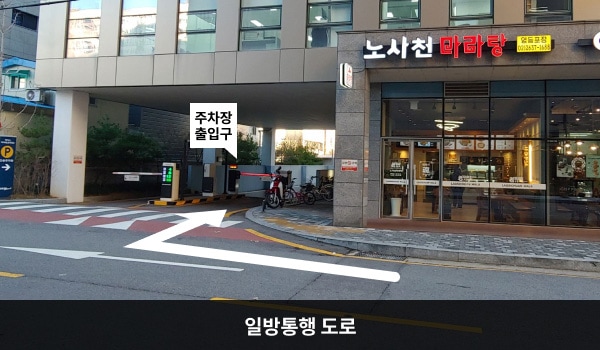 영등포서비스센터의 건물 좌측에 주차장 출입구가 있으며, 출입구 앞은 양방향 도로입니다. 오른쪽에 '노사천 마라탕' 간판이 붙은 가게가 있습니다.