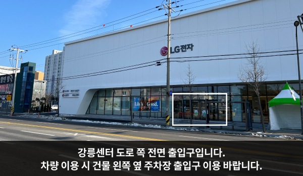 강릉서비스센터의 서비스센터 건물은 가로로 길고 흰색이며 1층에만 긴 유리창이 있습니다. 건물에 'LG전자'라고 쓰여 있습니다.
