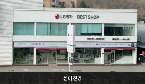 김포서비스센터의 서비스센터는 가로로 긴 건물이고 높이가 낮은 편입니다. 건물 위 간판에 흰색 바탕, 검정 글씨로 'LG전자 BEST SHOP & 서비스센터'라고 쓰여 있습니다.