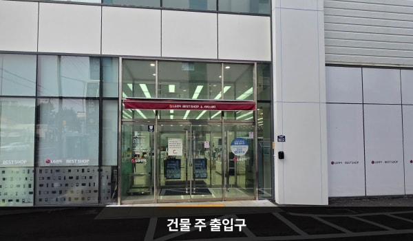 서귀포서비스센터의 건물 오른쪽, 주 출입구 위에는 붉은색 차양막이 있습니다. 문 앞에 점자블록이 있고, 양쪽 유리문 안쪽에 긴 손잡이가 있습니다. 문을 열고 들어가면 자동문이 하나 더 있습니다.
