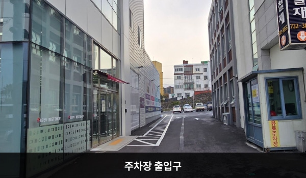 서귀포서비스센터의 건물 뒤쪽에 지상 주차장이 있습니다. 건물 오른쪽과 그 옆 건물 사이에 주차장으로 들어가는 출입구가 있습니다.