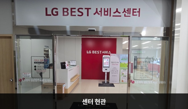 서귀포서비스센터의 센터 현관 위쪽에 'LG BEST 서비스센터'라는 문구가 적혀 있으며, 그 아래에 유리로 된 자동문이 있습니다. 문을 열고 들어가면 왼쪽에 안내데스크, 정면에 셀프 접수기가 있습니다.