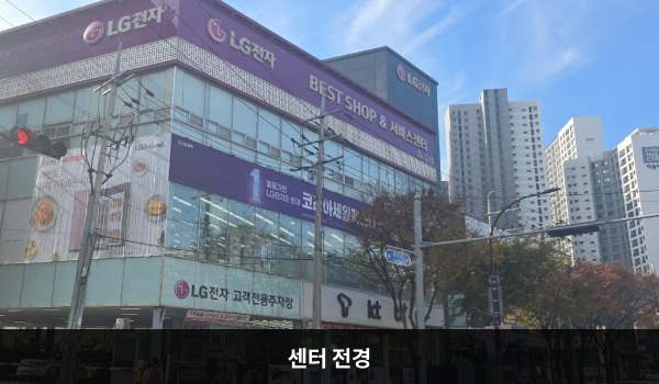 경산서비스센터의 서비스센터 건물은 유리창이 많습니다. 건물 위 간판에 흰색 글씨, 분홍색 바탕으로 'LG전자 BEST SHOP & 서비스센터'라고 쓰여 있습니다. 주차장은 1층, 서비스센터는 3층에 있습니다.