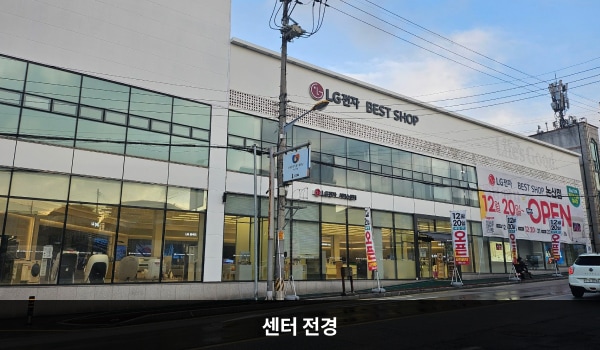 논산서비스센터의 건물 유리창이 크고 많습니다. 2층 붉은 간판에 'LG전자 BEST SHOP 베스트샵', 'LG전자 BEST 서비스센터'라고 적혀 있습니다.