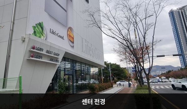 양산서비스센터의 서비스센터 건물 1층은 주차장입니다. 높은 흰색 건물이고 창문이 보이지 않습니다. 건물에 'LG전자'라고 쓰여 있습니다.