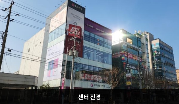 김천서비스센터의 건물 4층에 'LG전자 BEST SHOP & 서비스센터'라고 적힌 간판이 있습니다. 1층은 주차장으로 되어 있으며, 건물 유리창이 크고 많습니다.