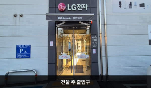 양주서비스센터의 건물 주 출입구 위에는 검은 바탕에 'LG전자' 문구가 적혀 있습니다. 양쪽 유리문 안쪽에 긴 손잡이가 있으며, 문을 열고 들어가면 문이 하나 더 있습니다. 엘리베이터와 더 가까운 출입구는 건물 뒷면 주차장 쪽 출입구입니다.