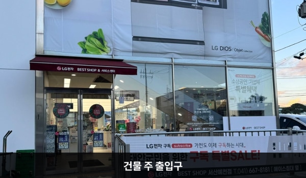서산서비스센터의 건물 정면에 주 출입구가 있습니다. 문 앞쪽에 점자블록과 경사진 턱이 있습니다. 양 유리문 안쪽에 긴 손잡이가 있습니다.