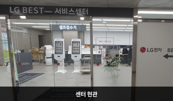 구리서비스센터의 센터 현관 위쪽에 'LG BEST 서비스센터'라는 문구가 적혀 있으며, 그 아래에 자동문이 있습니다. 문을 열고 들어가면 앞에 셀프 접수기가 있습니다.