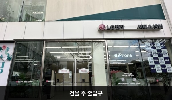 춘천서비스센터의 대로 앞, 건물 오른쪽에 여닫이문 출입구가 있습니다. 문 앞에 점자블록이 있습니다. 주차장을 통해 들어갈 수 있는 여닫이문 출입구가 있습니다.