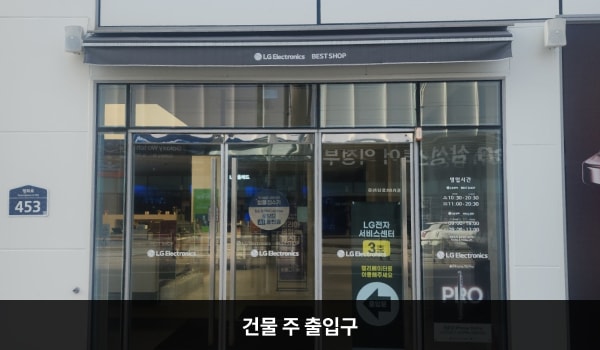 의정부서비스센터의 건물 주 출입구 위에는 회색 차양막이 있습니다. 유리문으로 되어 있으며, 양쪽 문 안쪽에 긴 손잡이가 있습니다.